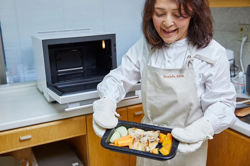 写真：出来上がった料理をヘルシオから取り出す勝間さん